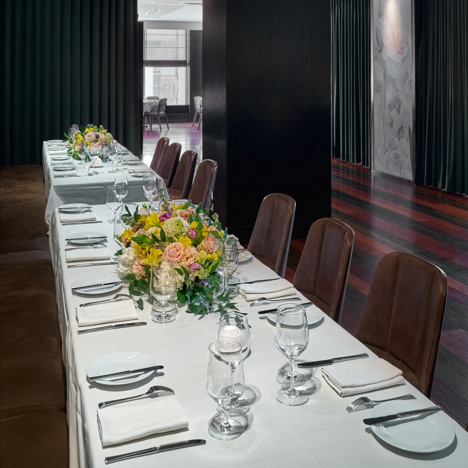 A long rectangular table with a banquet on one side and brown leather chairs on the other